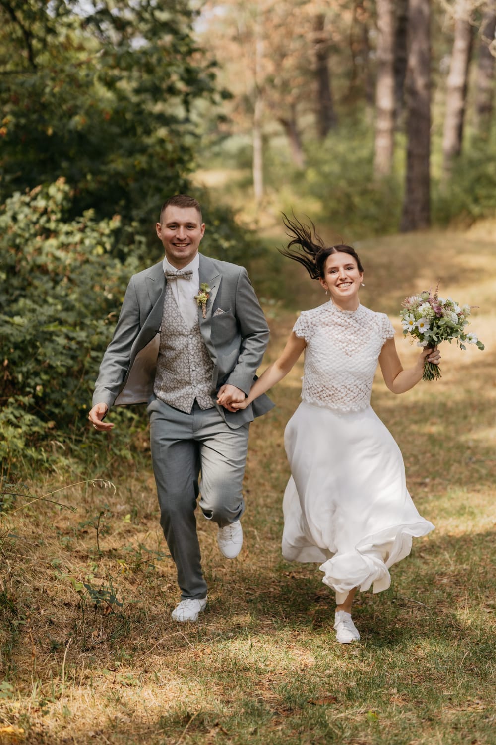 Hanna und Darius laufen lachend Hand in Hand durch den Wald